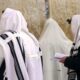 Extracting Sparks from Stones Orthodox Jews wearing tallit shawls are praying with Siddur prayer books at the Western/Wailing Wall or Kotel, holiest site in Judaism; Jerusalem Israel