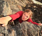 A view directly above a young woman climbing a rock face. She is determined to succeed.