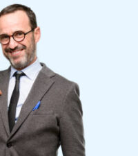 Teacher man using glasses proud, excited and arrogant, pointing with victory face isolated over blue background